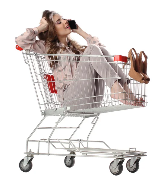 Woman talking on mobile phone from shopping trolley — Stock Photo, Image