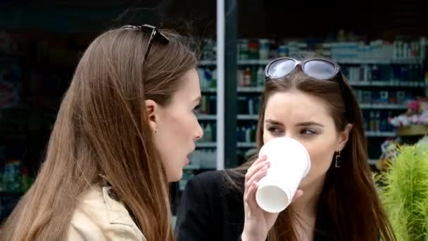 Dos chicas tomando café en el banco frente al centro de negocios — Vídeos de Stock