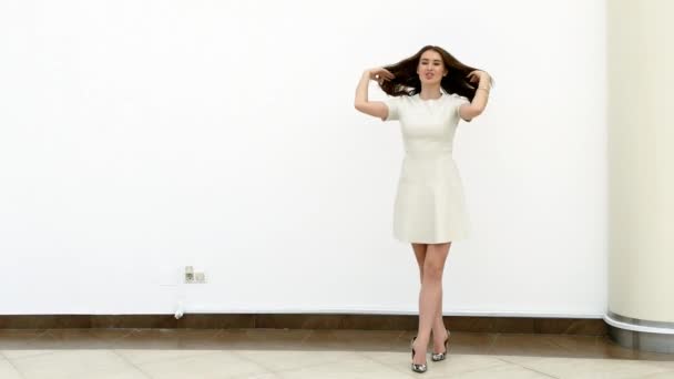 Счастливая женщина идет рядом с белой стеной — стоковое видео