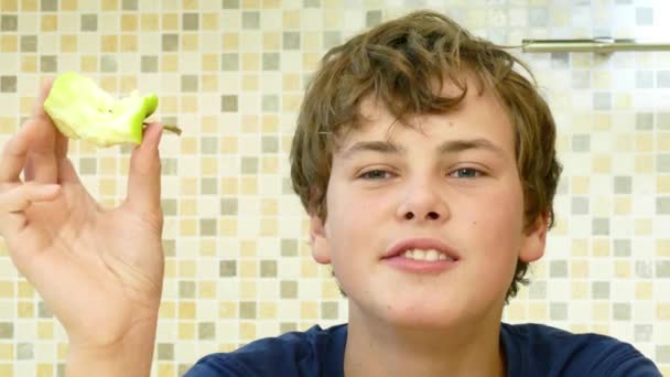 Niño feliz comiendo una manzana verde con placer . — Vídeo de stock