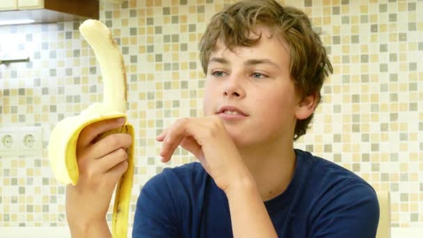 Jeune garçon manger une banane avec plaisir . — Video