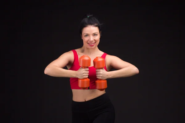 Жестокая атлетичная женщина накачивает мускулы гантелями — стоковое фото