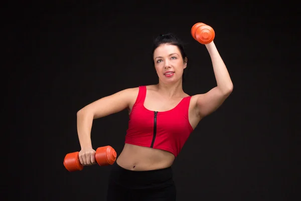 Жестокая атлетичная женщина накачивает мускулы гантелями — стоковое фото