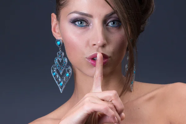 Mantener la señal de silencio de la mujer que lleva pendiente azul brillante — Foto de Stock