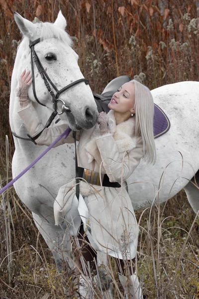 Menina loira com cavalo branco no pôr do sol de pé juntos — Fotografia de Stock