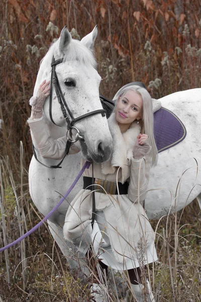 Menina loira com cavalo branco no pôr do sol de pé juntos — Fotografia de Stock