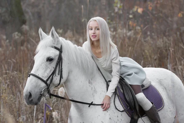 Två blonda, flicka med en häst på fältet — Stockfoto