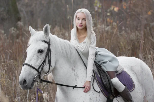 Två blonda, flicka med en häst på fältet — Stockfoto