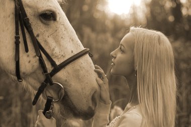 Sarışın ve beyaz at üzerinde gün batımından birbirlerinin gözlerine bakıyor