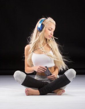 Gülümseyen kadın yerde kulaklıklarıyla oturuyor.