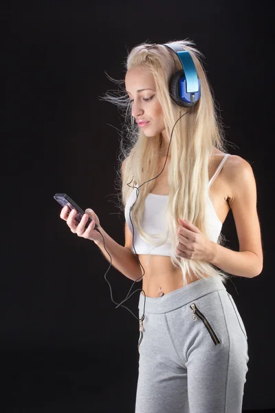 Ung kvinna med hörlurar och telefon — Stockfoto