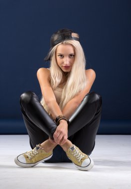 Mavi arka plan üzerinde oturan çekici sarışın kadın