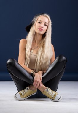 Mavi arka plan üzerinde oturan çekici sarışın kadın