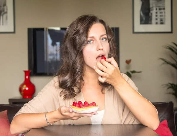 Kvinna äta tårta med hallon hemma — Stockfoto