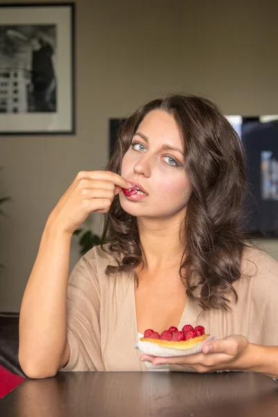 Vrouw eten thuis cake met frambozen — Stockfoto
