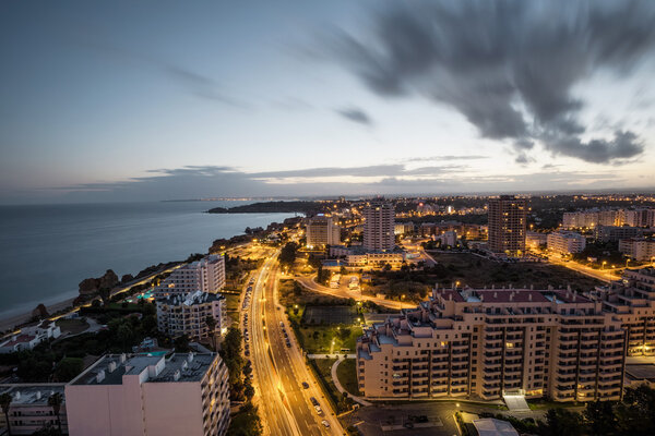 City at the bank of the ocean during sunset.