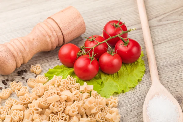 Massas, tomates e pimenta em um fundo de madeira — Fotografia de Stock