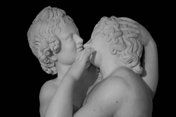 Couple of young statue are kissing, isolated on black background. Kiss marble ancient sculpture — Stock Photo, Image