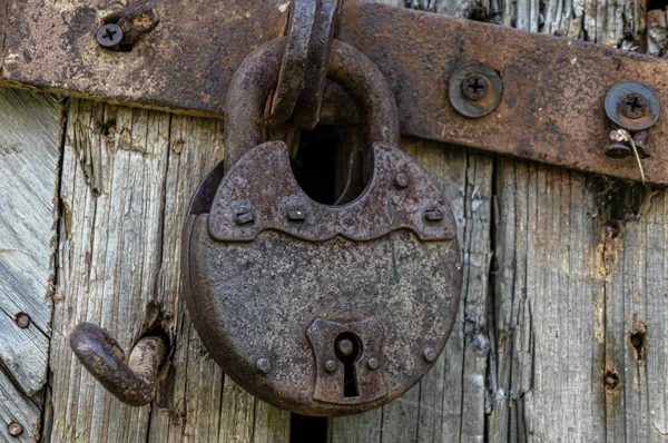 Oud roestslot op de deur. Metalen slot op de poort van een oude boerderij. Een echte dorpsstijl. Roest stalen vergrendeling vergrendeld met ijzeren slot — Stockfoto