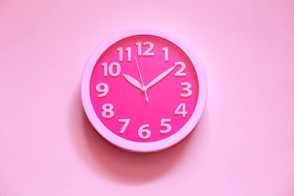 Horloge rose sur mur peint en rose. Concept de temps minimal. Réveillon de Noël ou idée de nouvel an. Horloge analogique élégante suspendue au mur, espace pour le texte — Photo