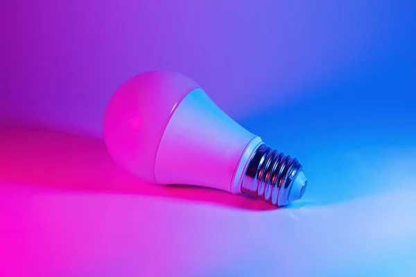 Foto de lâmpada levou lâmpada em luz de néon. Ideia conceito isolado em fundo azul rosa, para manutenção eletricista, artesão, faz-tudo — Fotografia de Stock