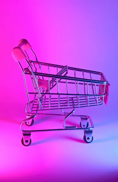 Carro de compras con luz de neón de moda. Gradiente rosa-azul resplandor. Arte conceptual. Retro 80. Concepto de compras minimalista. Carro de compras de juguete, neón —  Fotos de Stock