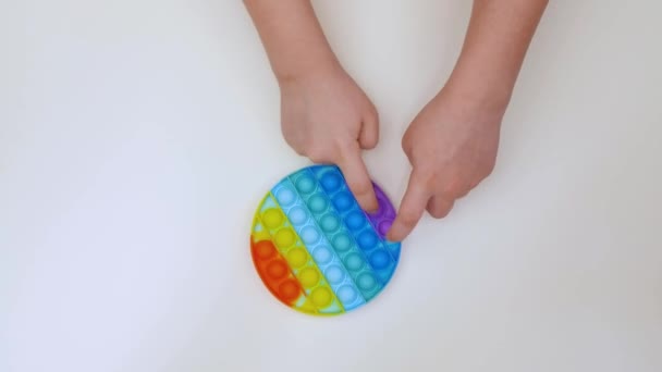 Popit Antistress Spielzeug für Kinder Unterhaltung auf gelbem Hintergrund spielt ein Kind Draufsicht in farbigem Fijit einfache Grübchen Popit Silikon Fidget, trendige sensorische Farbe drücken — Stockvideo