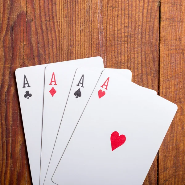 Four aces vintage poker game playing cards on a weathered wood table in an old western frontier gambling establishment saloon — Stock Photo, Image