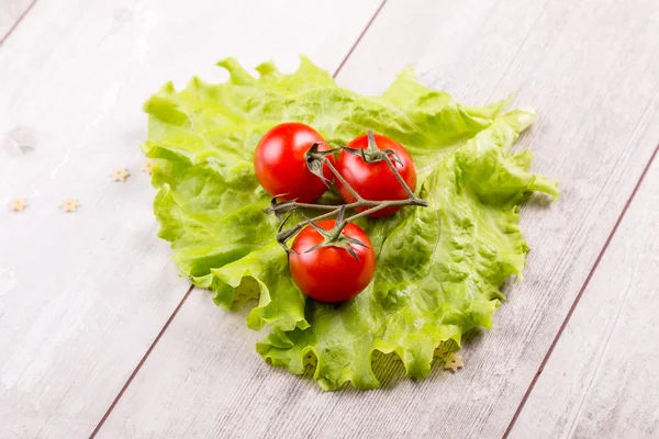 Tomate e salada verde sobre fundo de madeira — Fotografia de Stock