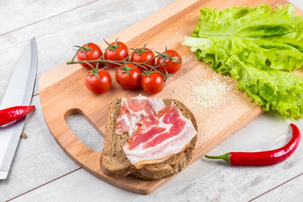 Tomat, rostat bröd, kött och sallad på träbord — Stockfoto