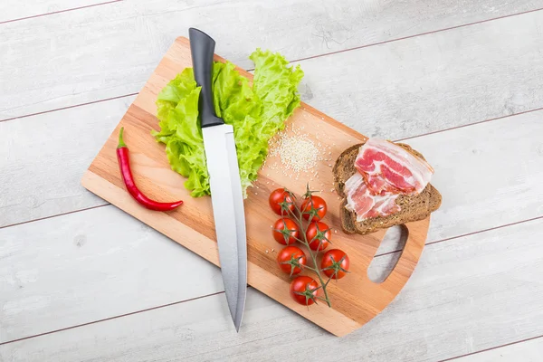 Rajčata, toasty, maso a salát na dřevěný stůl — Stock fotografie