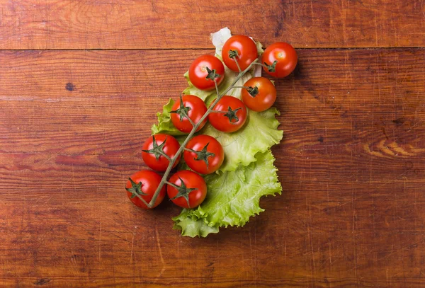 Tomates cereja frescos e maduros em uma velha tábua de cortar . — Fotografia de Stock