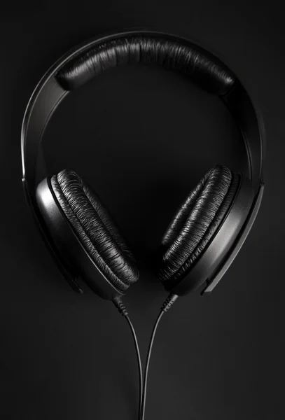 Fones de ouvido preto em um fundo preto — Fotografia de Stock