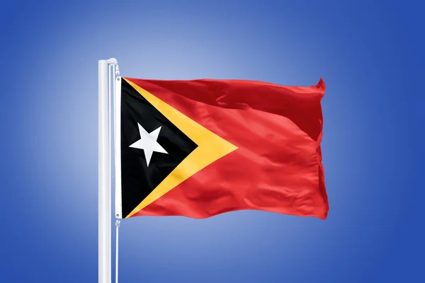 Vlajka Východního Timoru létal proti modré obloze — Stock fotografie