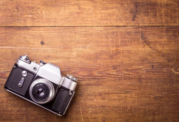 Retro fotoaparát na dřevěné tabulce pozadí — Stock fotografie