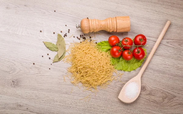 Těstoviny, rajčata a papriky na dřevěné pozadí — Stock fotografie