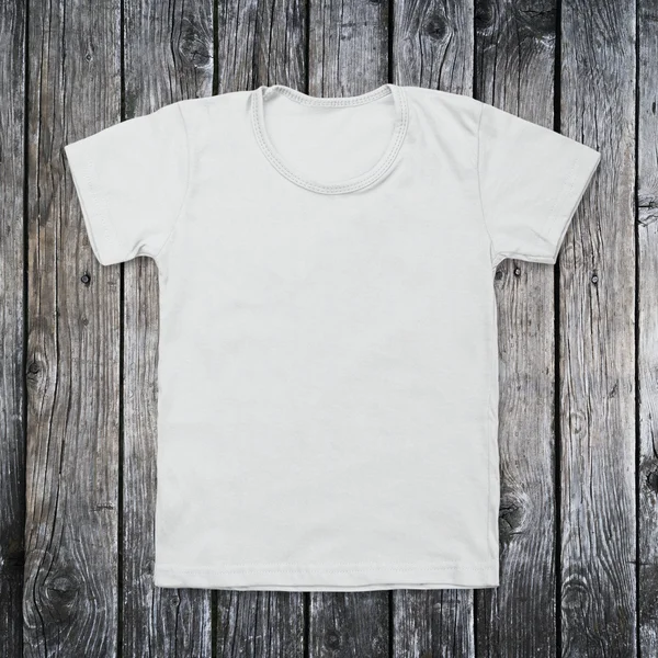 White blank t-shirt on dark wood desk — Stock Photo, Image