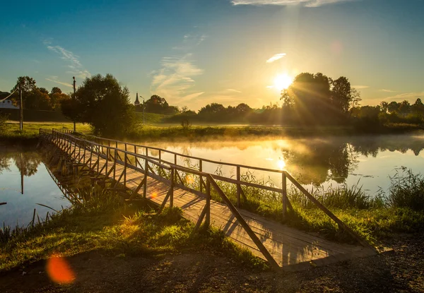 Puente de madera a través del río a la luz del sol — Foto de Stock
