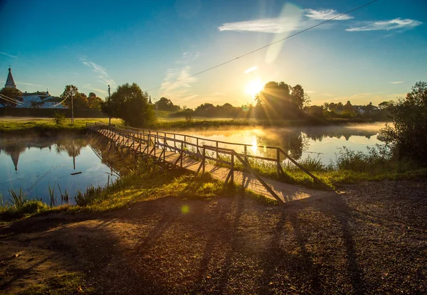 Holzbrücke durch Fluss in der Morgensonne — Stockfoto