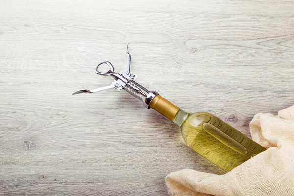 Fles wijn met corkscrew op houten achtergrond — Stockfoto