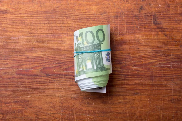 Roll of one hundred euro banknotes on wood — Stock Photo, Image