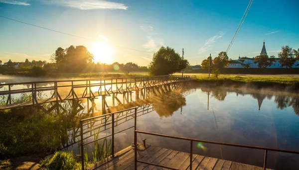 Puente de madera a través del río a la luz del sol — Foto de Stock