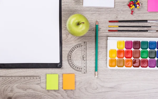 Papper, pennor, borste, grönt äpple på träbord — Stockfoto
