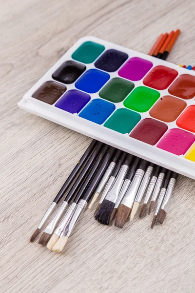 Watercolor paints with brushes on wood — Stock Photo, Image