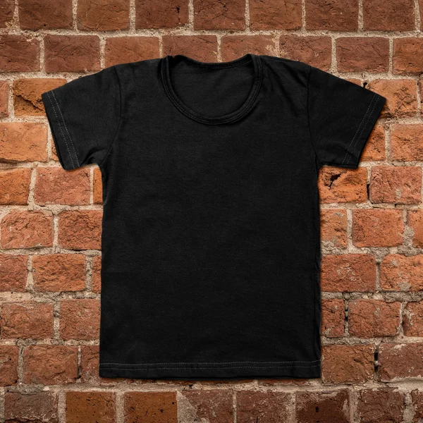 Czarny t-shirt puste na tle ciemnej cegły — Zdjęcie stockowe