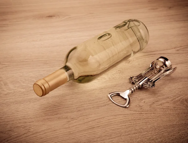 Wine bottle with corkscrew on wooden background — Stock Photo, Image