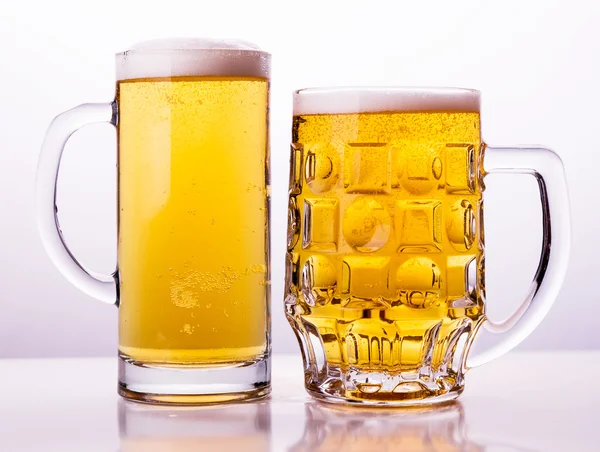 Две кружки свежего пива с пеной в шапке — стоковое фото