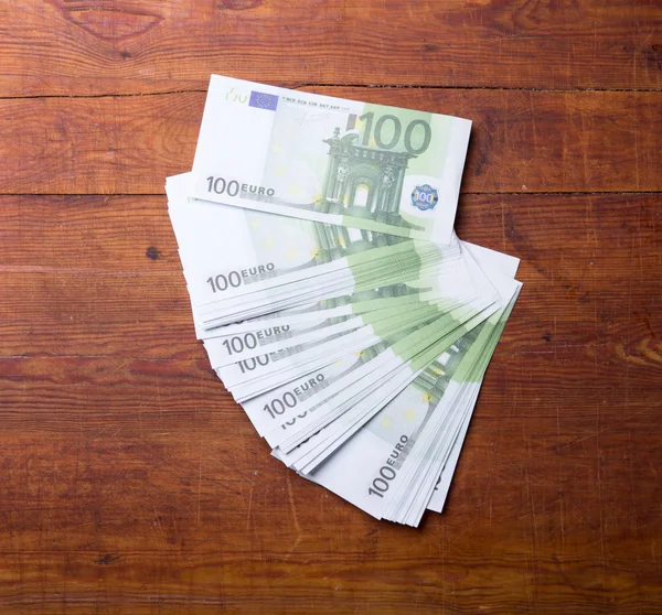 Primo piano di 100 banconote in euro su fondo legno . — Foto Stock