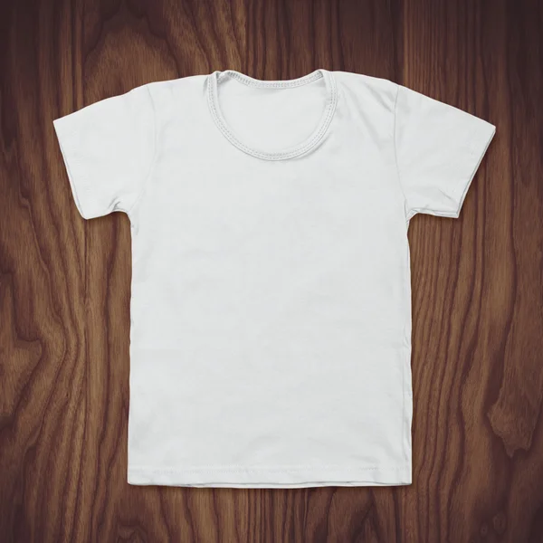 White blank t-shirt on dark wood desk — Stock Photo, Image