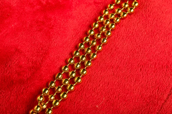 Christmas golden beads on red background — Stock Photo, Image